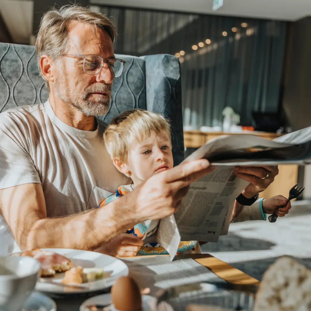 Großvater sitzt mit seinem Enkel auf dem Sofa und liest gemeinsam