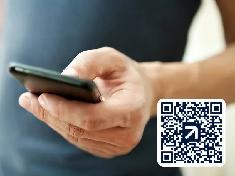 Hand mit Smartphone und rechts unten in der Ecke ist ein QR-Code, der zur Raisin-App führt