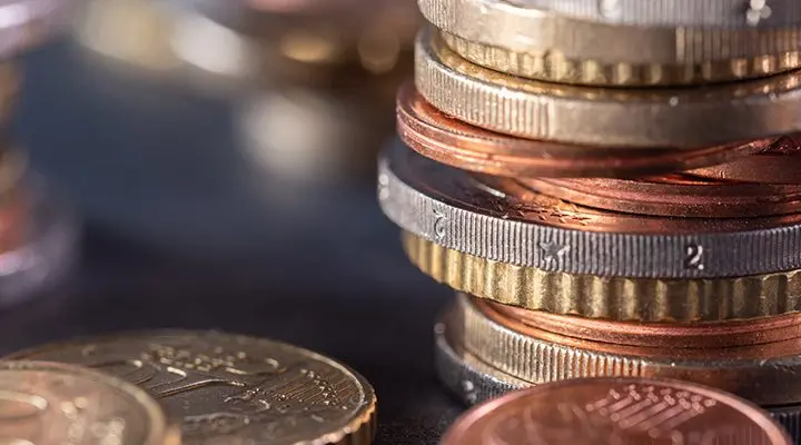 Varias columnas de monedas superpuestas sobre superficie oscura con reflejos.