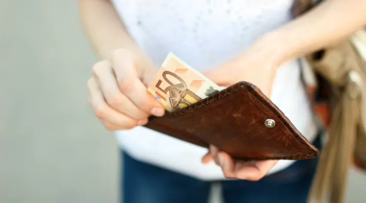 Mano saca 50 euros de una cartera. La imagen se utiliza para representar la previsión de los tipos de interés en 2025.