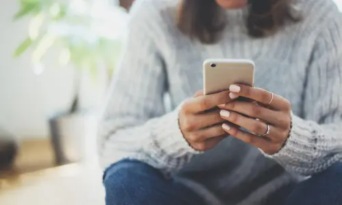 Raisin UK-Person holding smartphone A close up of hands holding a mobile phone.