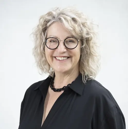 raisin-uk-samantha-secomb.jpg A photo of Samantha Secomb. She has blonde, shoulder-length curly hair, round glasses and is wearing a black shirt.