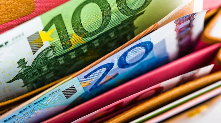 Verschillende eurobankbiljetten liggen verspreid in een portemonnee.