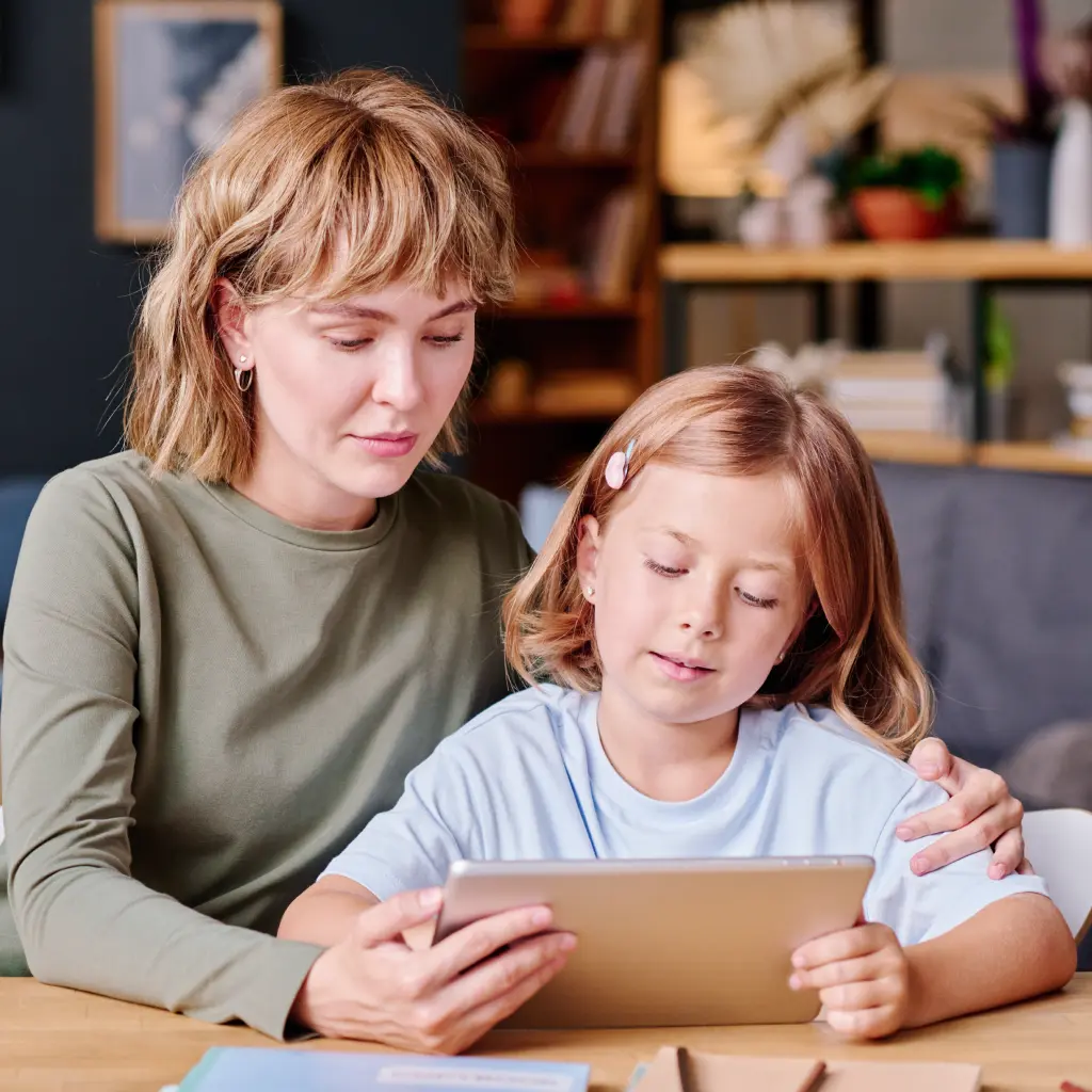 raisin_de_mutter_und_tochter_lernen_zusammen_am_tablet.png Raisin DE- Mutter unterstützt ihr Kind beim Lernen am Tisch und erklärt gemeinsam Schulaufgaben