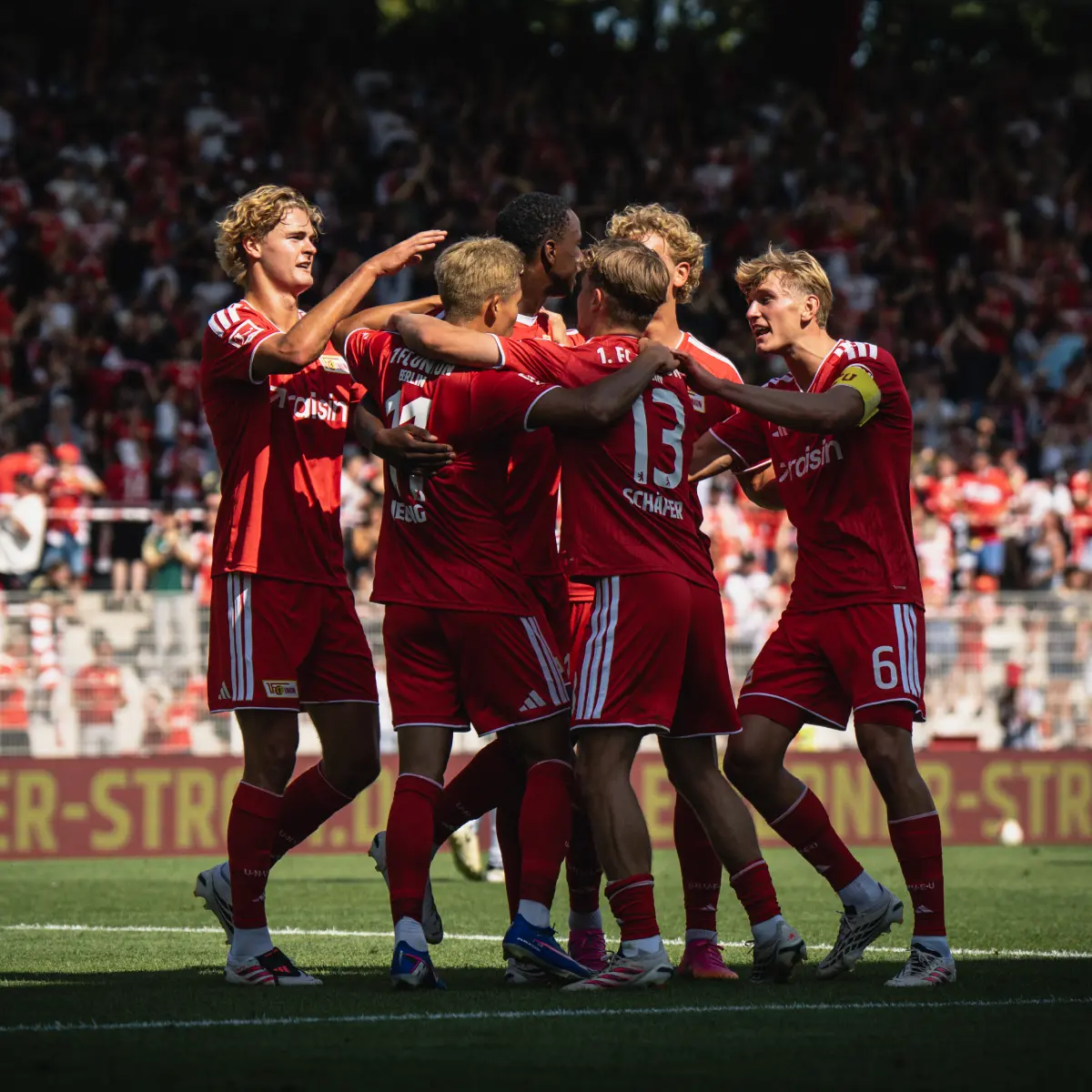 Werbegrafik mit zwei Fußballspielern des 1. FC Union Berlin in der Umkleidekabine, beide tragen rot-weiße Trikots mit Raisin-Logo. Daneben ein rotes Signet mit dem Vereinslogo und dem Hinweis ‚Hauptsponsor 2025–2026‘. Unten Text: ‚Jetzt Tickets gewinnen: Mit Raisin zum 1. FC Union Berlin‘.