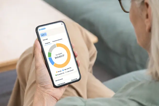 Hand holding phone featuring Raisin dashboard