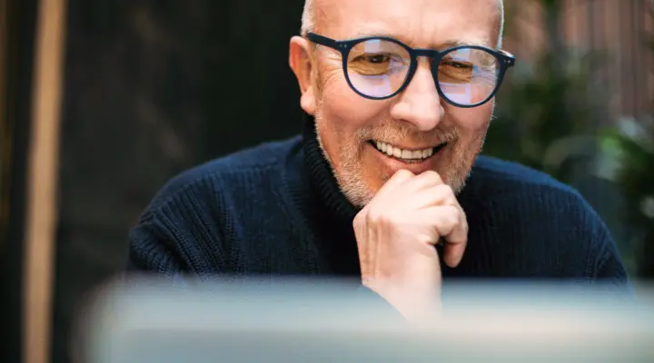 Un homme mature souriant utilisant son ordinateur portable