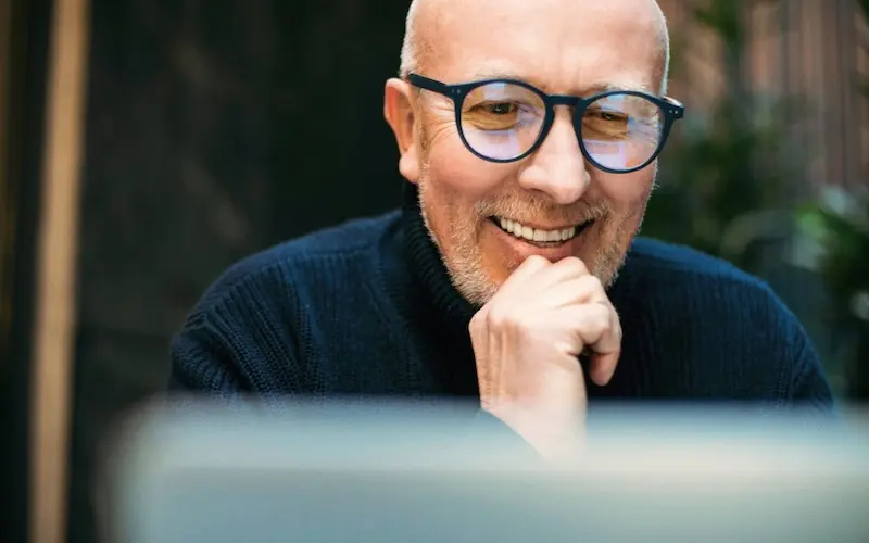Uomo felice che guarda schermo del laptop