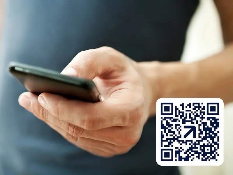 raisin_fi_qr_app_download_mobile.jpg Lähikuva henkilöstä, joka pitelee älypuhelinta kädessään. Henkilöllä on tumma paita yllään. Kuvan oikeassa alakulmassa on QR-koodi. Tarkennus on kädessä ja puhelimessa.