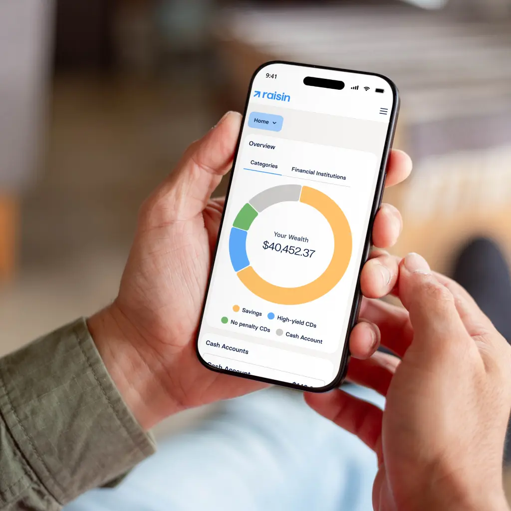 phone-app-lifestyle-v2.png A customer looks at the Raisin dashboard on their mobile device