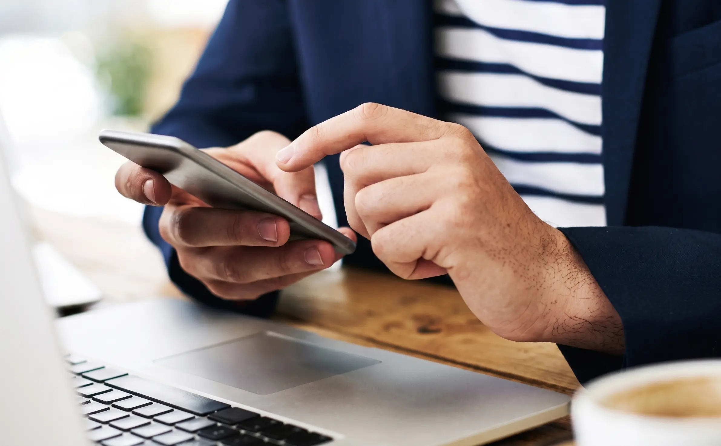 Man on phone behind laptop.png Persoon achter laptop op telefoon