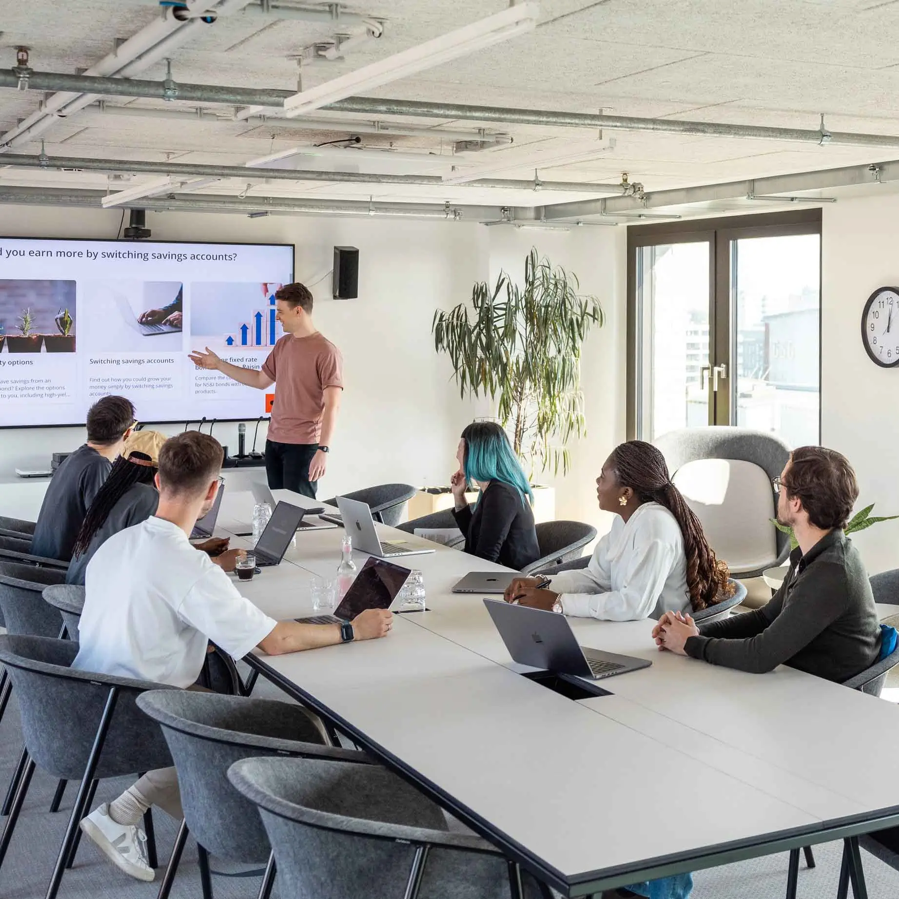 Raisin COM - Raisin colleagues in meeting room A number of colleagues are sitting in a meeting room, following a presentation held by another colleage at the board.