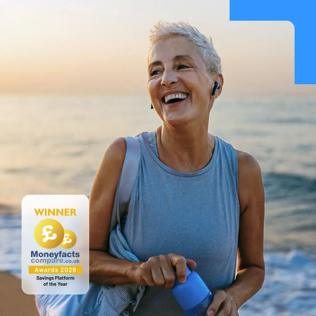A laughing mature woman in athletic wear on a beach. Features a Moneyfacts 2026 Savings Platform of the Year award badge.