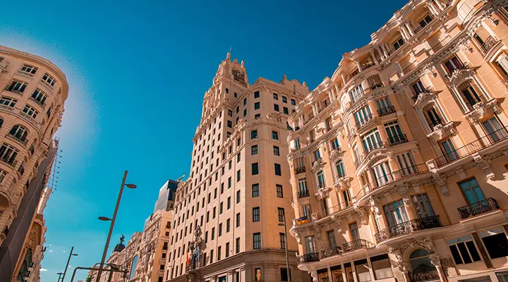 Fachada de edificio de viviendas con balcones y ventanas iluminadas por el sol.