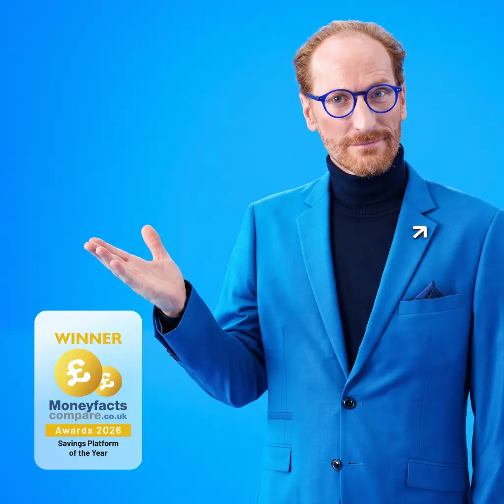 Man wearing a blue suit and glasses gesturing with an open palm against a solid blue background.