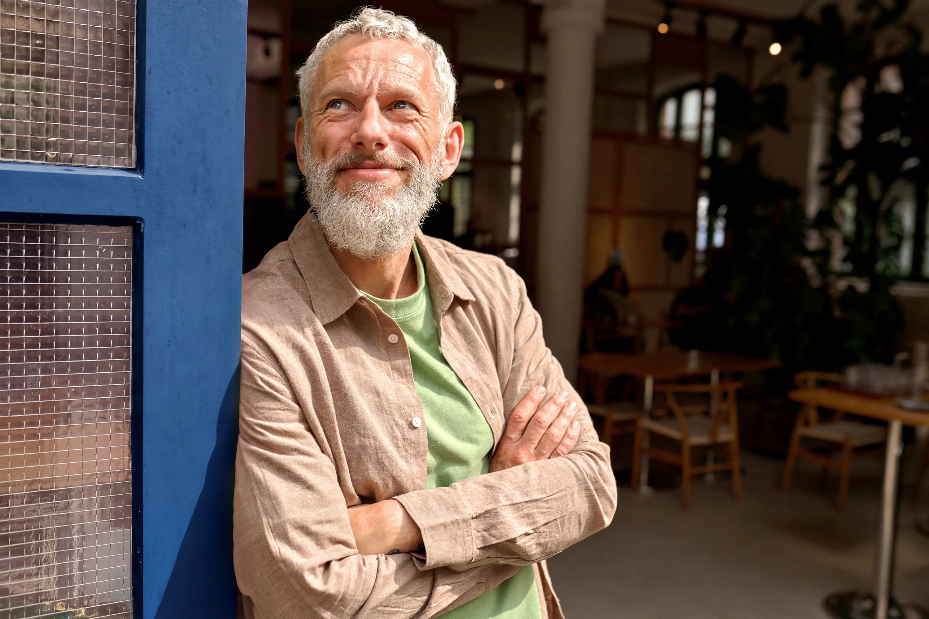 Un homme d'âge mûr souriant debout devant le pas de sa porte regardant vers le ciel